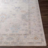Close-up of Rochedale Area Rug. Cream rug with lavender, olive, and pale blue traditional pattern on dark wood floor. Front