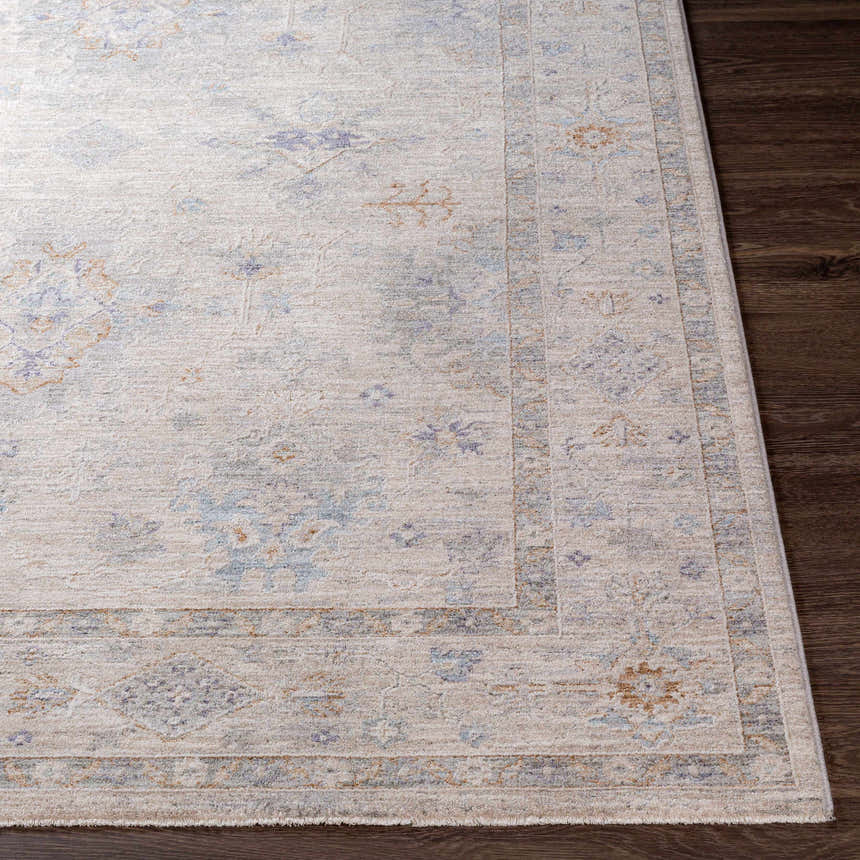 Close-up of Rochedale Area Rug. Cream rug with lavender, olive, and pale blue traditional pattern on dark wood floor. Front