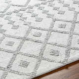 Close-up of the hand-woven Rick Area Rug. Features a geometric pattern in arctic stone and gray on a textured, flatweave surface. Texture