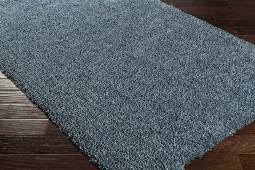 Close up of the teal Rocklake Clearance Rug showing its shag texture on dark wood floors. Corner