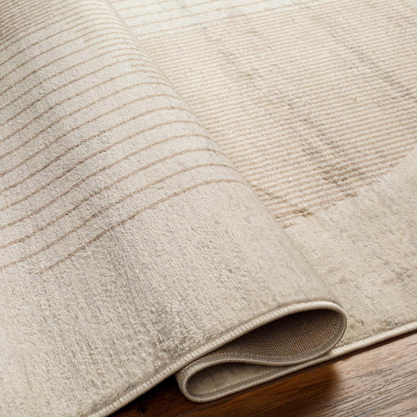 Close-up of the Zeke Geometric Nutmeg Rug showing its soft texture and subtle brown striped pattern. Fold