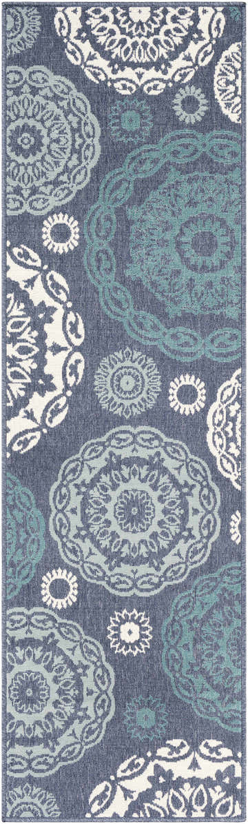 Close-up of the Reasnor Area Rug. Navy olefin rug with pale blue, teal, and white floral medallion pattern. Design-Runner