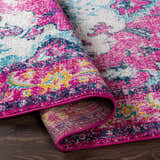 Close-up of the Reedham Magenta Area Rug showing its fuchsia, blue, yellow, and cream contemporary design. Fold