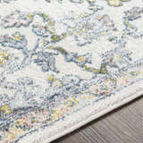 Close-up of the Reubens Area Rug showing its ivory base and blue, yellow, and peach bohemian-style pattern. Texture