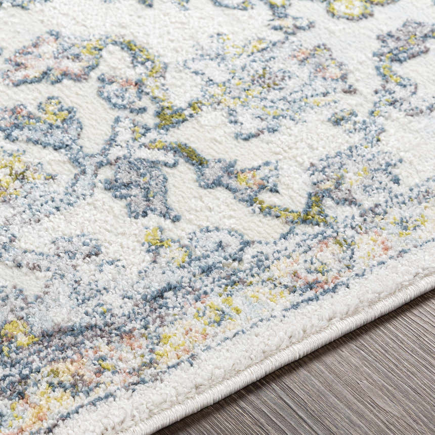 Close-up of the Reubens Area Rug showing its ivory base and blue, yellow, and peach bohemian-style pattern. Texture
