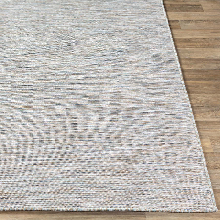 Close-up of the Revillo Area Rug, featuring a woven texture in light sage, tan, gray, teal, and white on a wood floor. Front