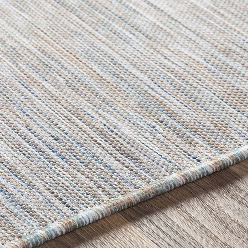 Close-up of the Revillo Area Rug showing light sage, gray, tan, teal, and white woven texture. Texture