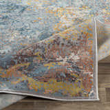 Close-up of the Argo Area Rug showing its contemporary abstract design in aqua, brown, mustard, and gray on a wood floor. Fold