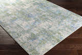 Close-up of the Riegelwood Area Rug. Light beige rug with medium gray, green, navy, and blue abstract pattern. Corner