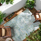 Coastal sunroom with the Riegelwood Area Rug, wooden chairs, and lush green plants. Roomscene-Rectangle