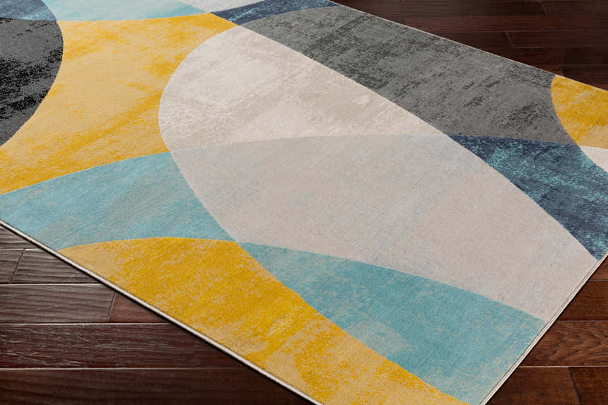 Close-up of Ringgold Area Rug with aqua, charcoal, light slate, mustard, peach, and taupe geometric design. Corner