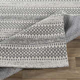 Close-up of the Ringtown Washable Area Rug in charcoal and ivory. Features a geometric, woven pattern and cotton texture. Fold