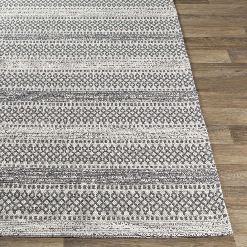 Close-up of Ringtown Washable Area Rug in charcoal and ivory. Bohemian style rug with geometric pattern and machine woven texture. Front