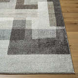 Close-up of Raisa Area Rug showing a contemporary geometric pattern in aqua, black, cream, gray, and light brown on wood floor. Front
