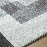 Close-up of the Raisa Area Rug showing its geometric pattern in aqua, black, cream, light gray, and light brown. Texture