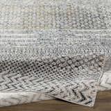 Close-up of the Rombauer Area Rug, showcasing its charcoal, gray, and off-white contemporary pattern and machine-woven texture. Fold