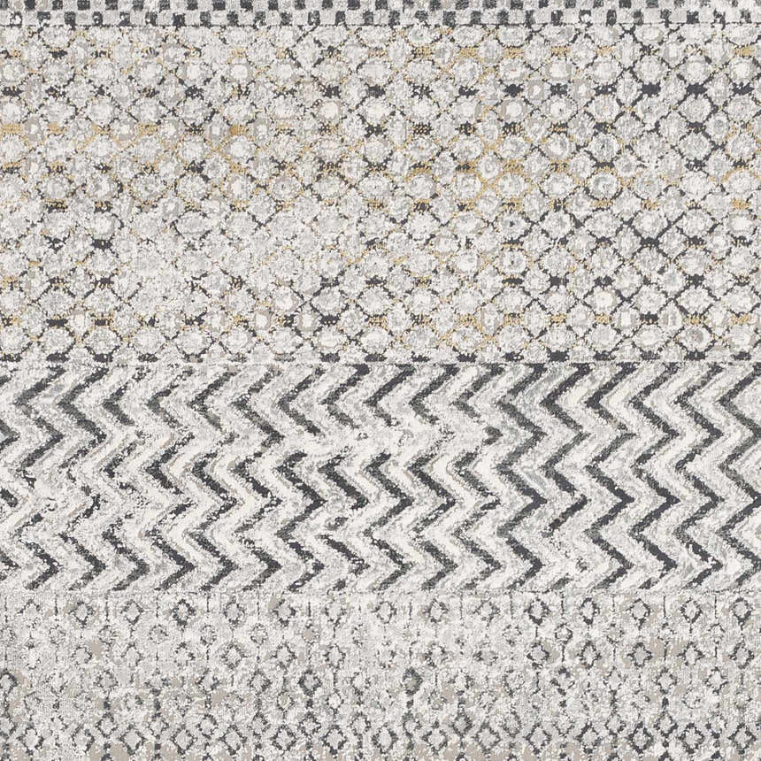 Close-up of the Rombauer Area Rug, showcasing its charcoal, gray, and off-white geometric pattern and distressed texture. Swatch