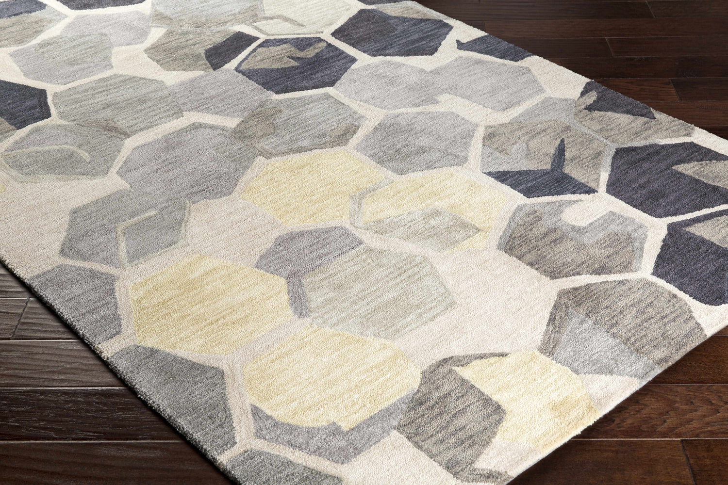 Close-up of the Romoland Area Rug, featuring a contemporary geometric pattern in gray, charcoal, and light beige tones. Corner