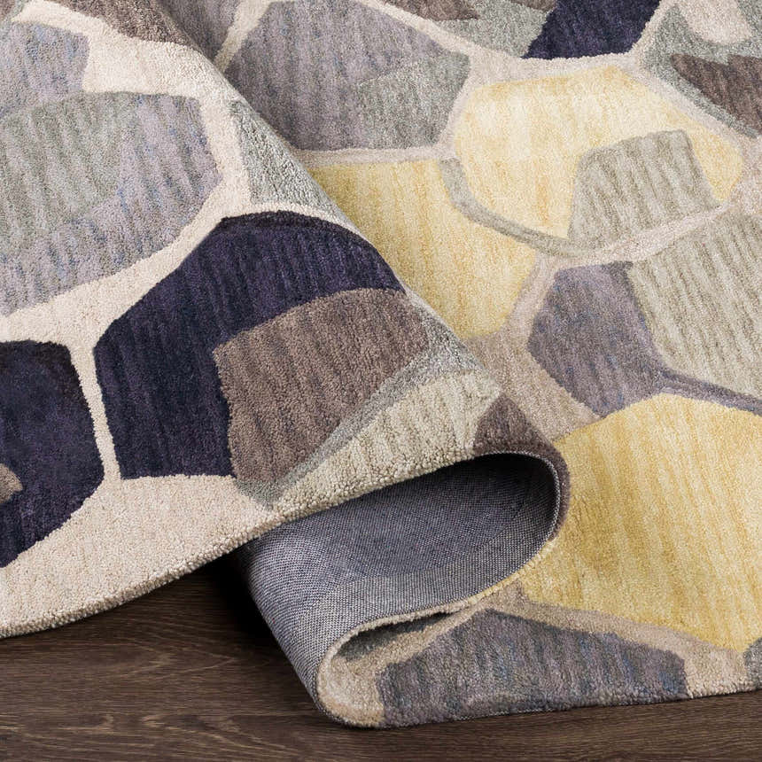 Close-up of the Romoland Area Rug showing its hand-tufted texture and contemporary pattern in black, brown, gray, and yellow tones. Fold