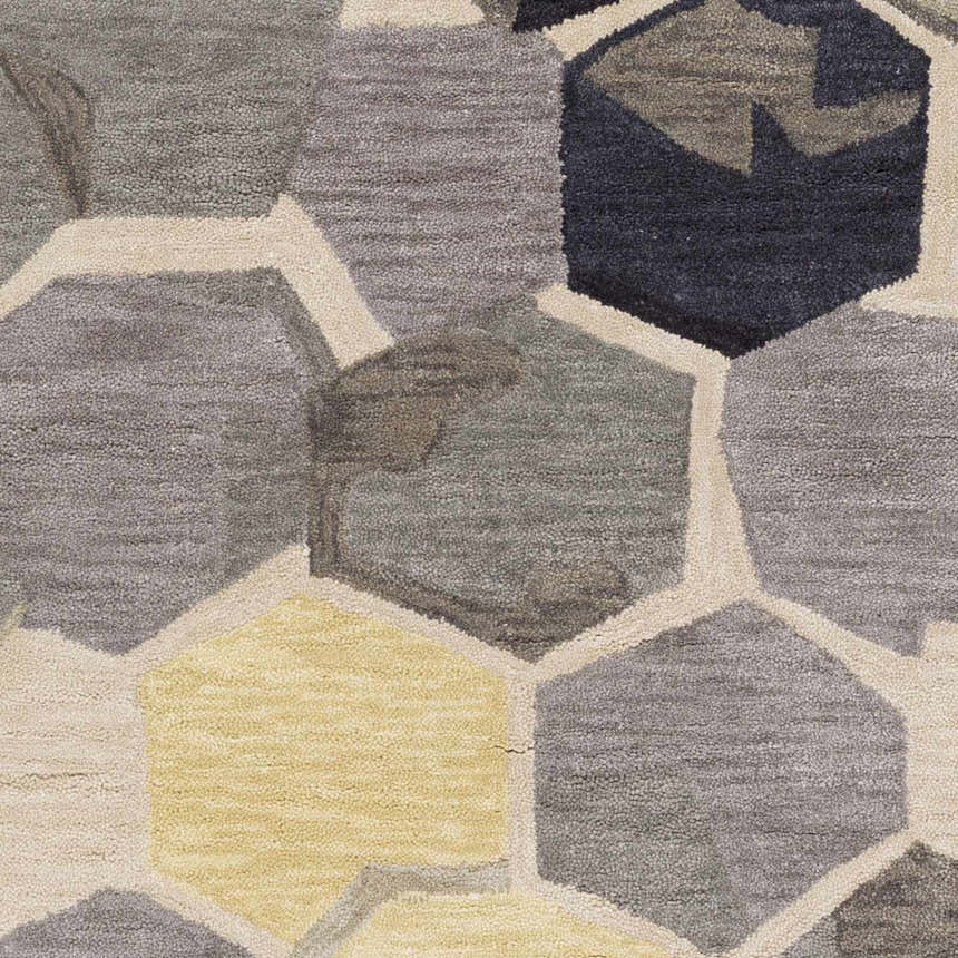 Close-up of the Romoland Area Rug. Hand-tufted polyester rug with a geometric hexagon pattern in black, gray, yellow, and beige. Swatch