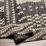 Close up of the hand woven Rossville Area Rug, black and cream geometric pattern. Fold
