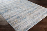 Close-up of Runa Area Rug showcasing its contemporary blue, brown, and off white abstract pattern and soft texture. Corner