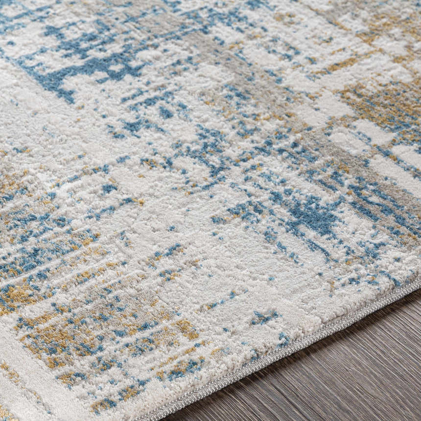 Close-up of the Runa Area Rug, a contemporary design in blue, mustard, and gray on an off-white base. Machine woven texture. Texture
