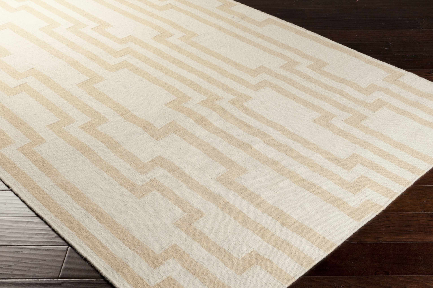 Close-up of Rushden Area Carpet, oatmeal and tan wool rug with a contemporary geometric pattern on dark wood floors. Corner