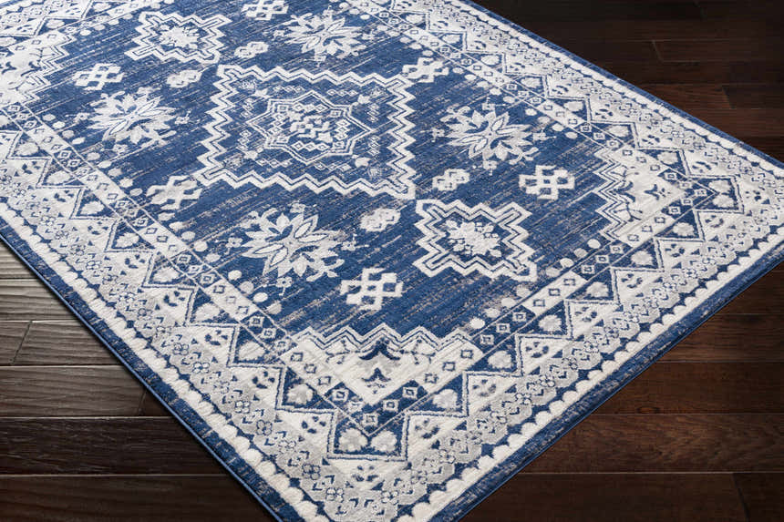 Ryton White&Blue Area Rug: Bohemian style rug with floral and geometric patterns in blue and white on dark wood floor. Corner