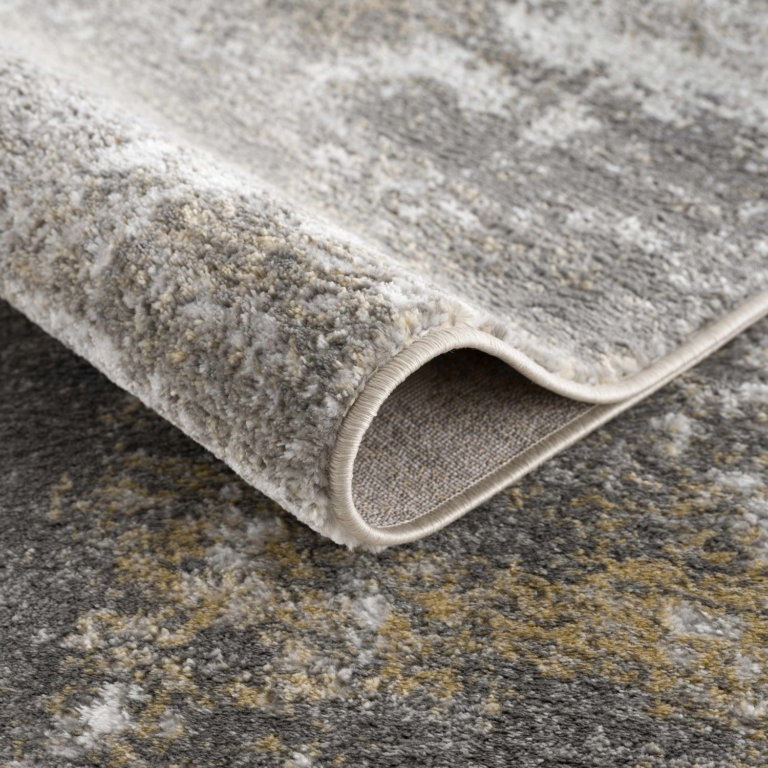 Close-up of the Liveree Abstract Area Rug, showcasing its light gray, rust, and off-white abstract pattern and machine-woven texture. Fold