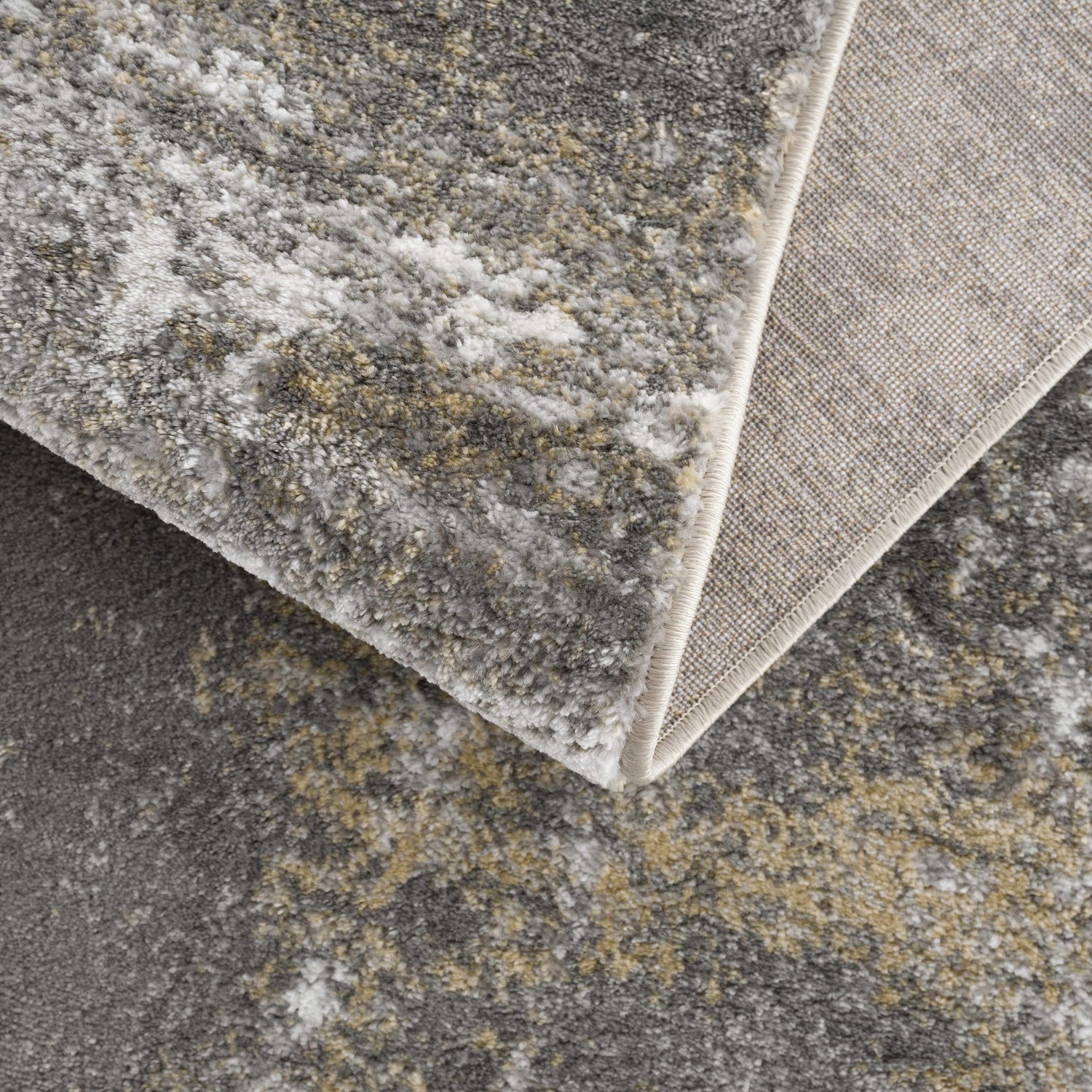 Close-up of the Liveree Abstract Area Rug showing light gray, medium gray, off white, and rust abstract design and woven texture. Fold