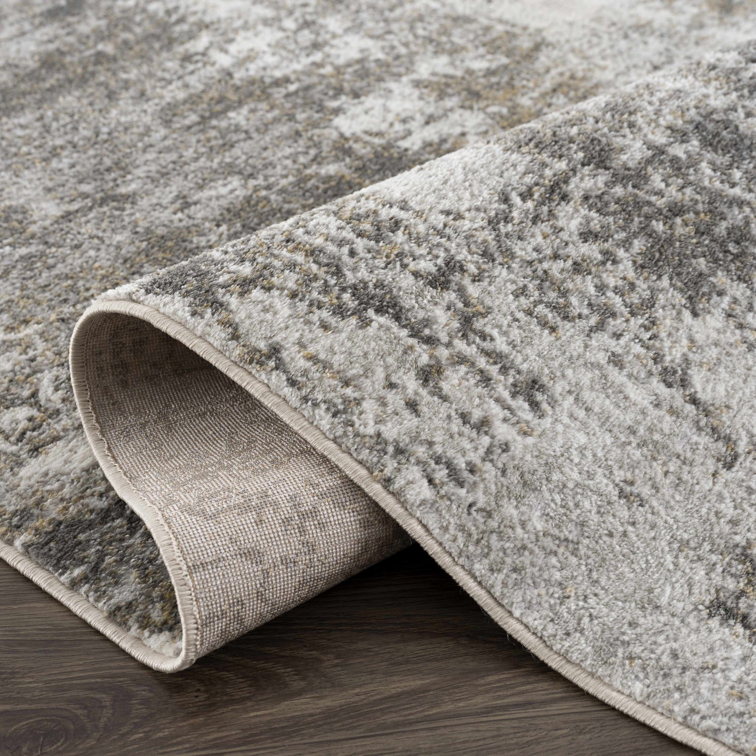 Close-up of the Liveree Abstract Area Rug showing light gray, medium gray, off white, and rust colors. Machine woven texture. Fold