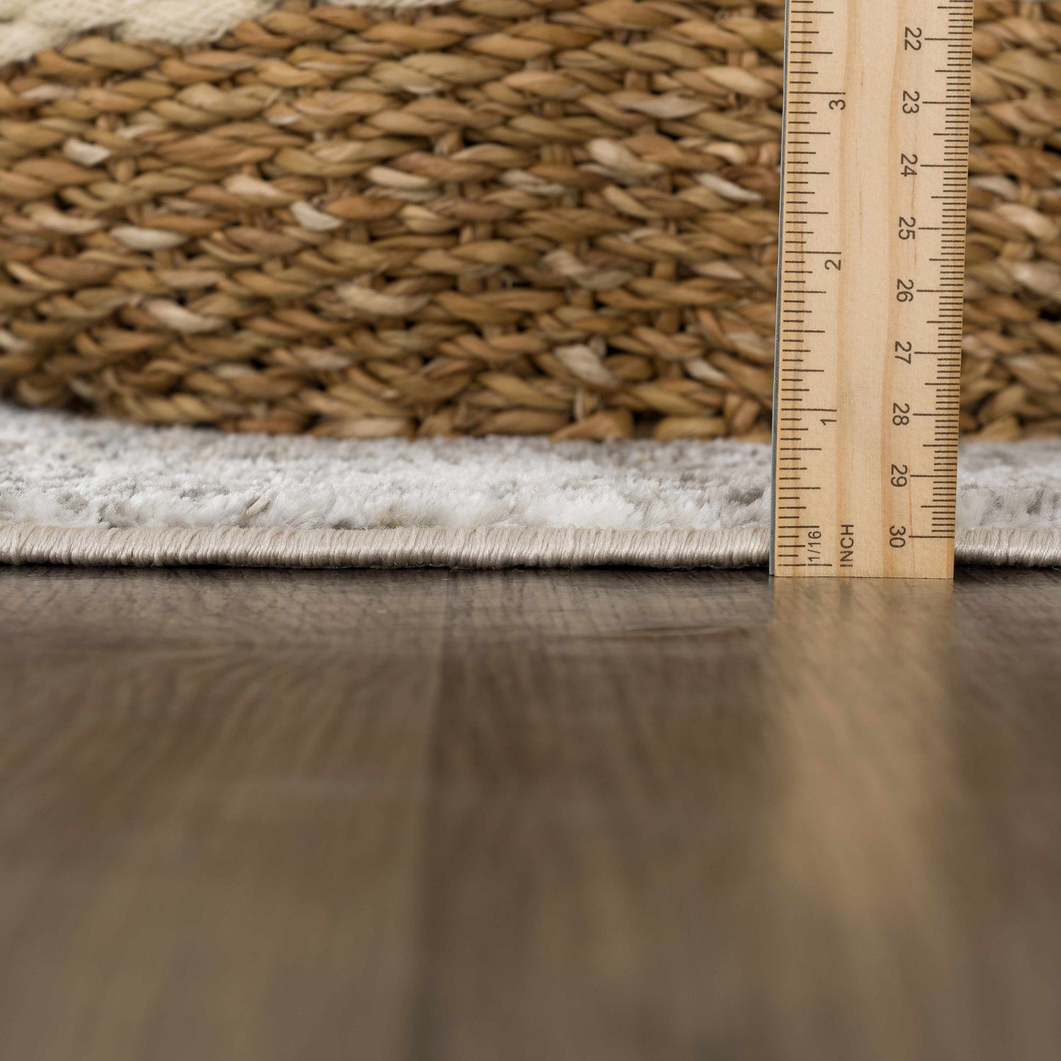 Close-up of the Liveree Abstract Area Rug showing pile height with ruler. Light gray and off-white rug texture detail. Pile