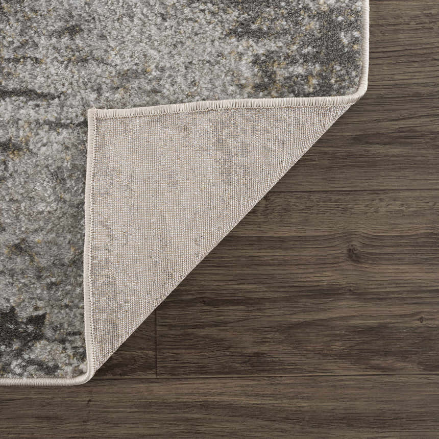 Close-up of the Liveree Abstract Area Rug showing light gray, medium gray, off white, and rust colors and woven backing. Fold