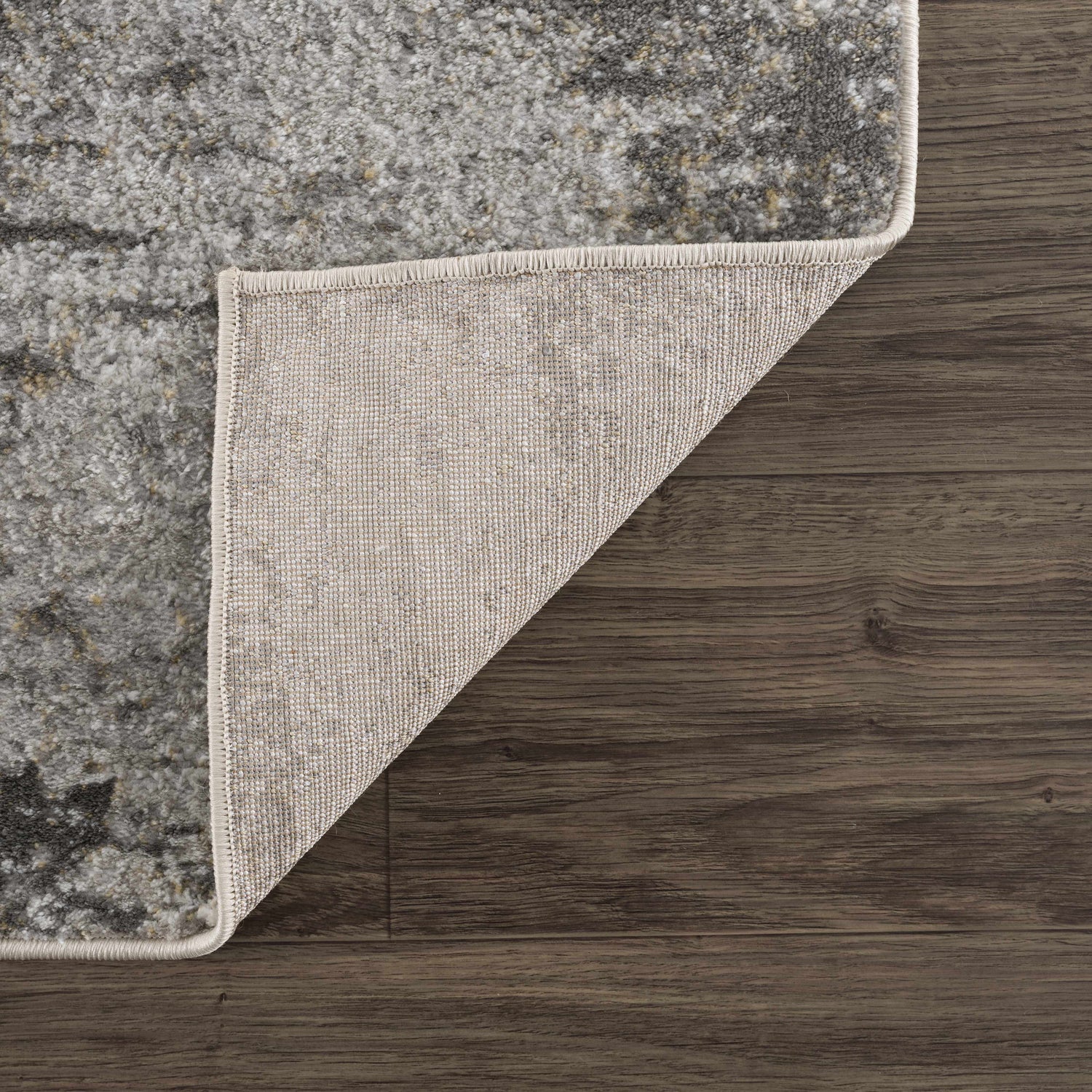 Close-up of the Liveree Abstract Area Rug showing light gray, medium gray, off white, and rust colors and woven backing. Fold