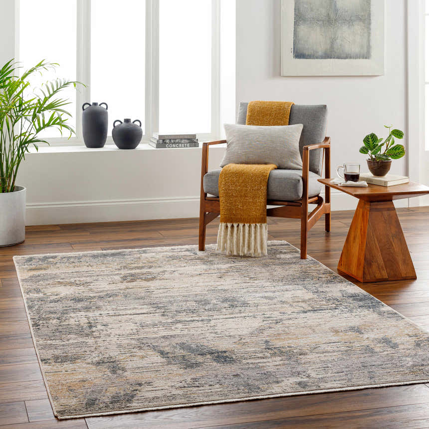 Living room scene with the Asuna Area Rug in beige, gray, and brown tones, styled with a modern chair and wood accents. Roomscene-Rectangle
