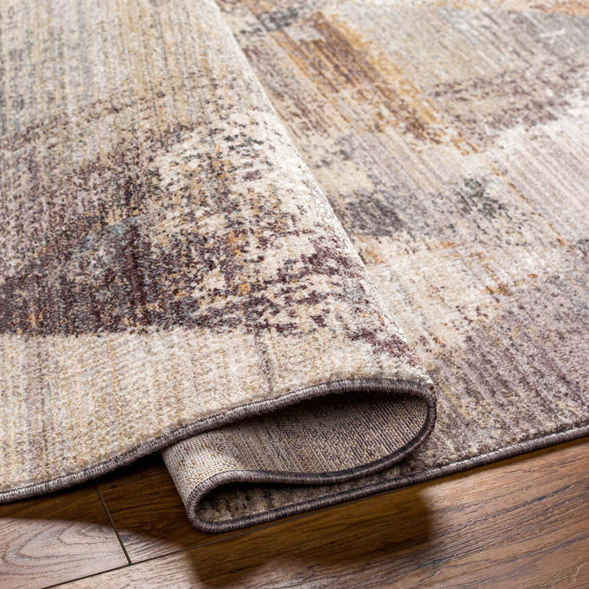 Close-up of the Birdy Area Rug showing its beige, brown, and gray contemporary design and soft, textured polyester material. Fold