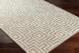 Close-up of the Fynn Beige Area Rug showing a geometric maze pattern in beige, bone, and gray on dark wood flooring. Corner