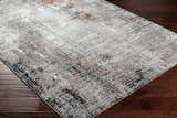 Close-up of the Ervin Gray Area Rug showing its abstract design, black, gray, ivory, and rust colors on dark wood flooring. Corner