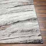 Close-up of Glain Gray & Brown Marble Area Rug showing the abstract pattern, colors, and soft texture next to hardwood flooring. Front