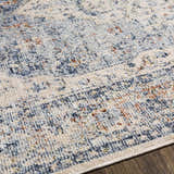 Close-up of the Salmo Area Rug showing its denim, cream, and brick red traditional pattern and soft polyester texture. Texture