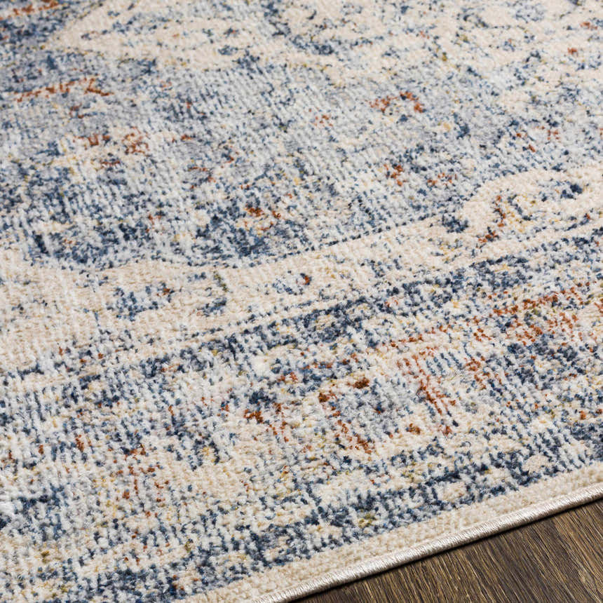 Close-up of the Salmo Area Rug showing its denim, cream, and brick red traditional pattern and soft polyester texture. Texture