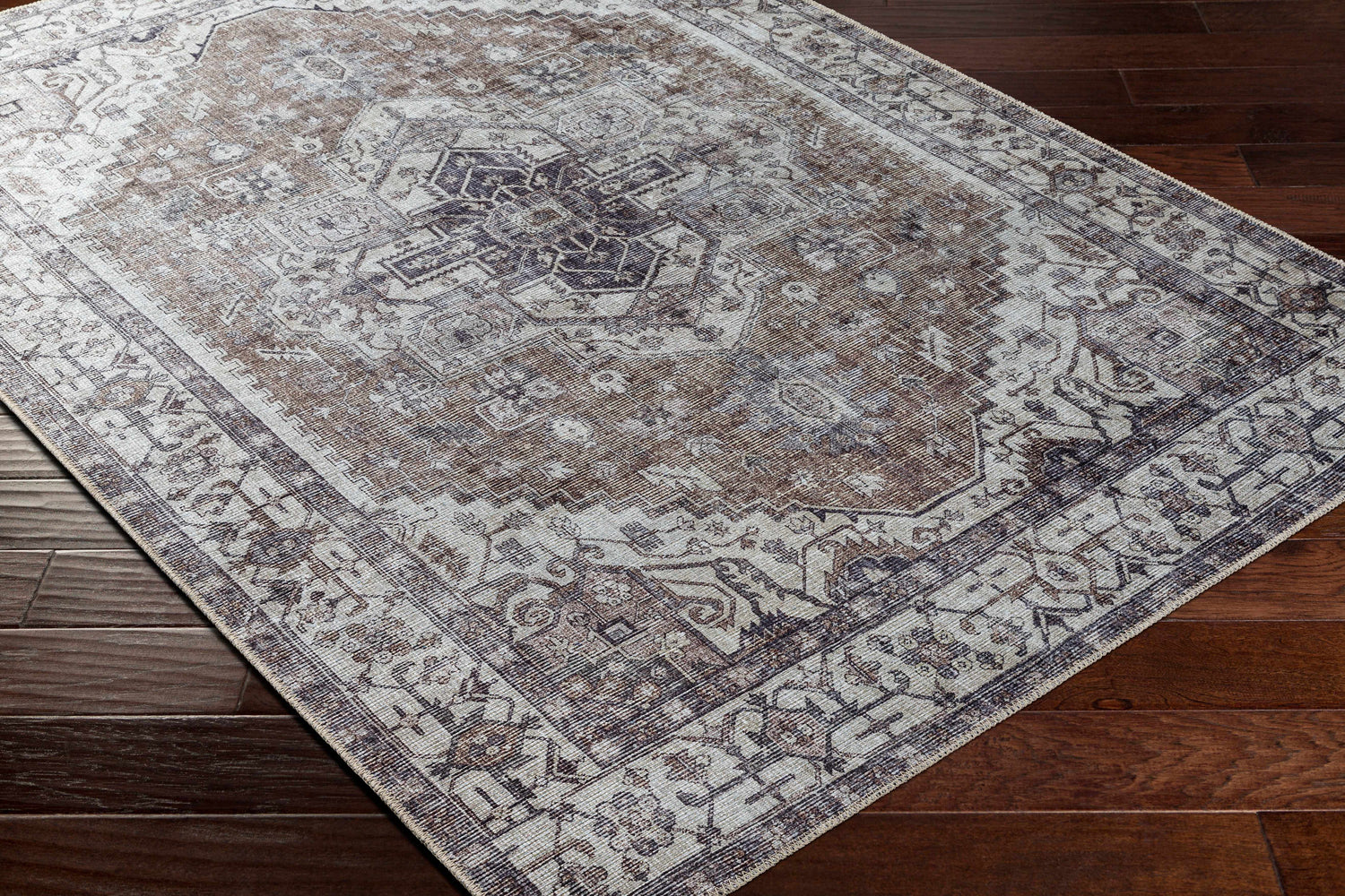 Close-up of the Athor Washable Rug. Farmhouse style rug in dark gray, eggplant, brown, natural gray, and taupe on wood floor. Corner