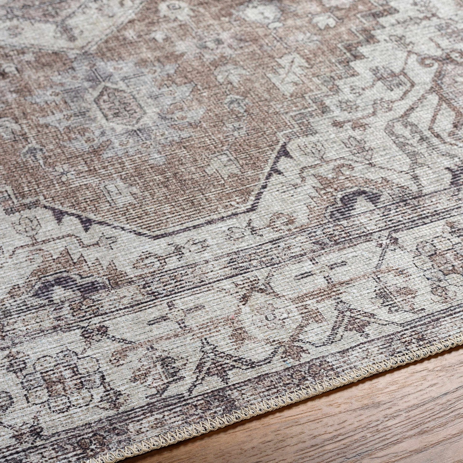 Close-up of the Athor Washable Rug showing its traditional brown, taupe, and gray pattern and machine woven texture. Texture