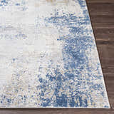 Close-up of the Sapcote Textured Luxe Area Rug. Abstract design with charcoal, blue, beige, and gray tones. Machine woven texture. Front
