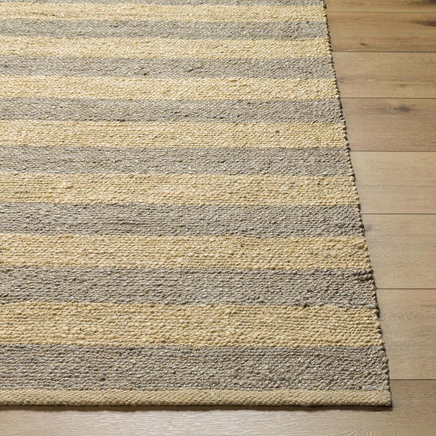 Close-up of the Ilkay Jute Area Rug showing its camel and natural jute stripes and hand-woven texture on a wood floor. Front