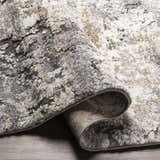 Close-up of the thick Satsop Rock Pattern Rug. Features black, charcoal, gray, ivory, and tan colors with a contemporary design. Fold