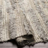 Close-up of the hand-knotted Saundersfoot Area Rug. Charcoal, gray, and light beige wool rug with a textured, bohemian design. Fold