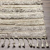 Close-up of the Saundersfoot Area Rug. Hand-knotted wool rug in charcoal, gray, and light beige with tassels. Front