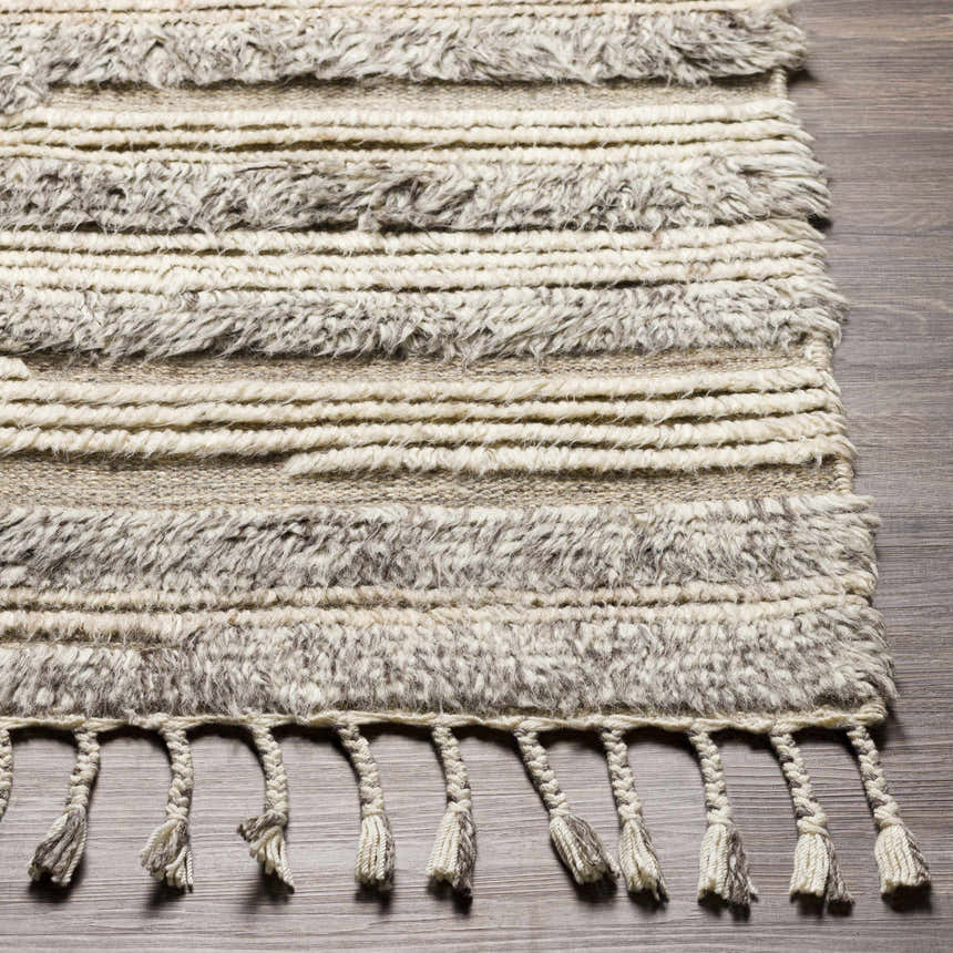 Close-up of the Saundersfoot Area Rug. Hand-knotted wool rug in charcoal, gray, and light beige with tassels. Front